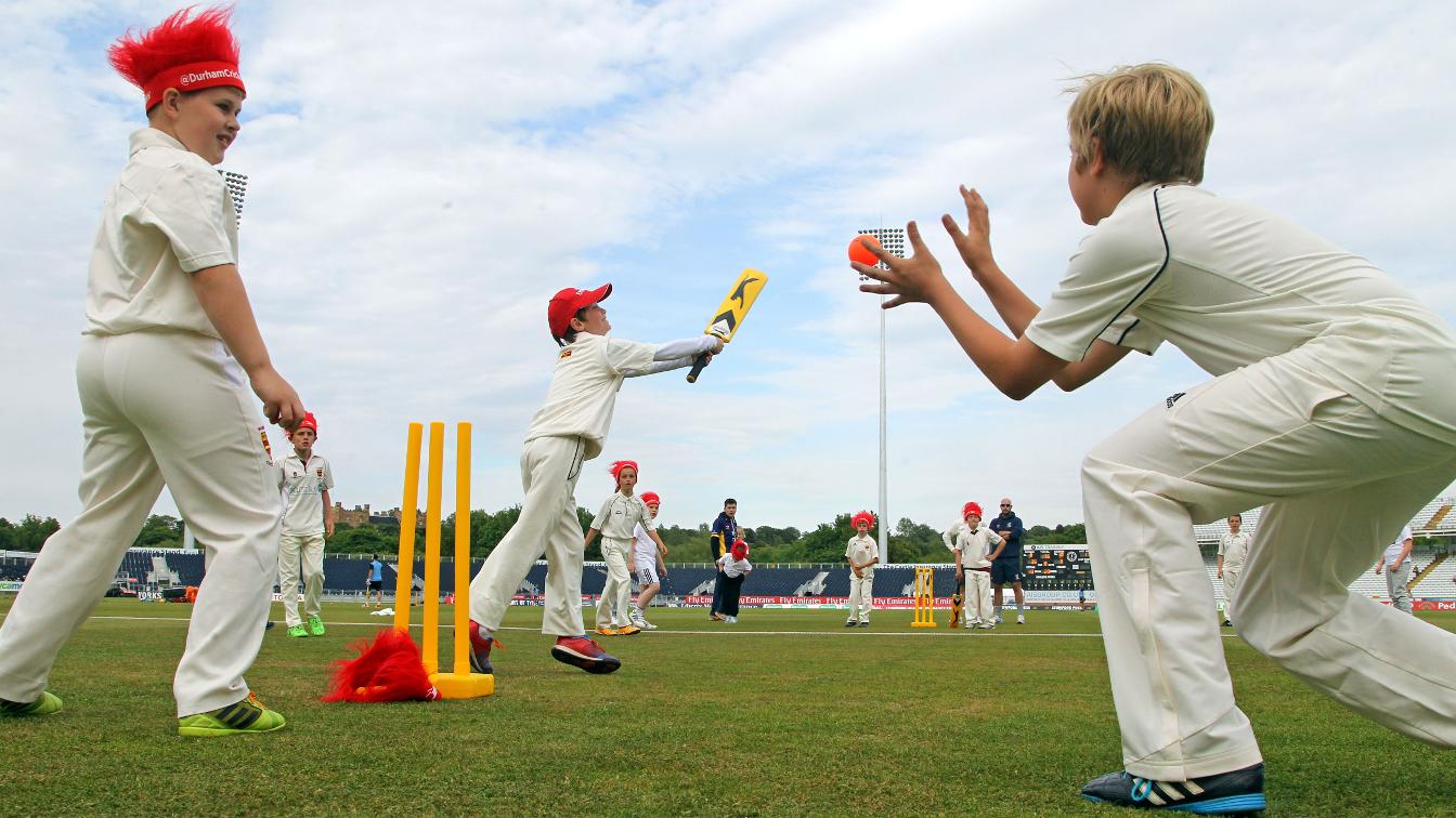 kids in red hats playing cricket