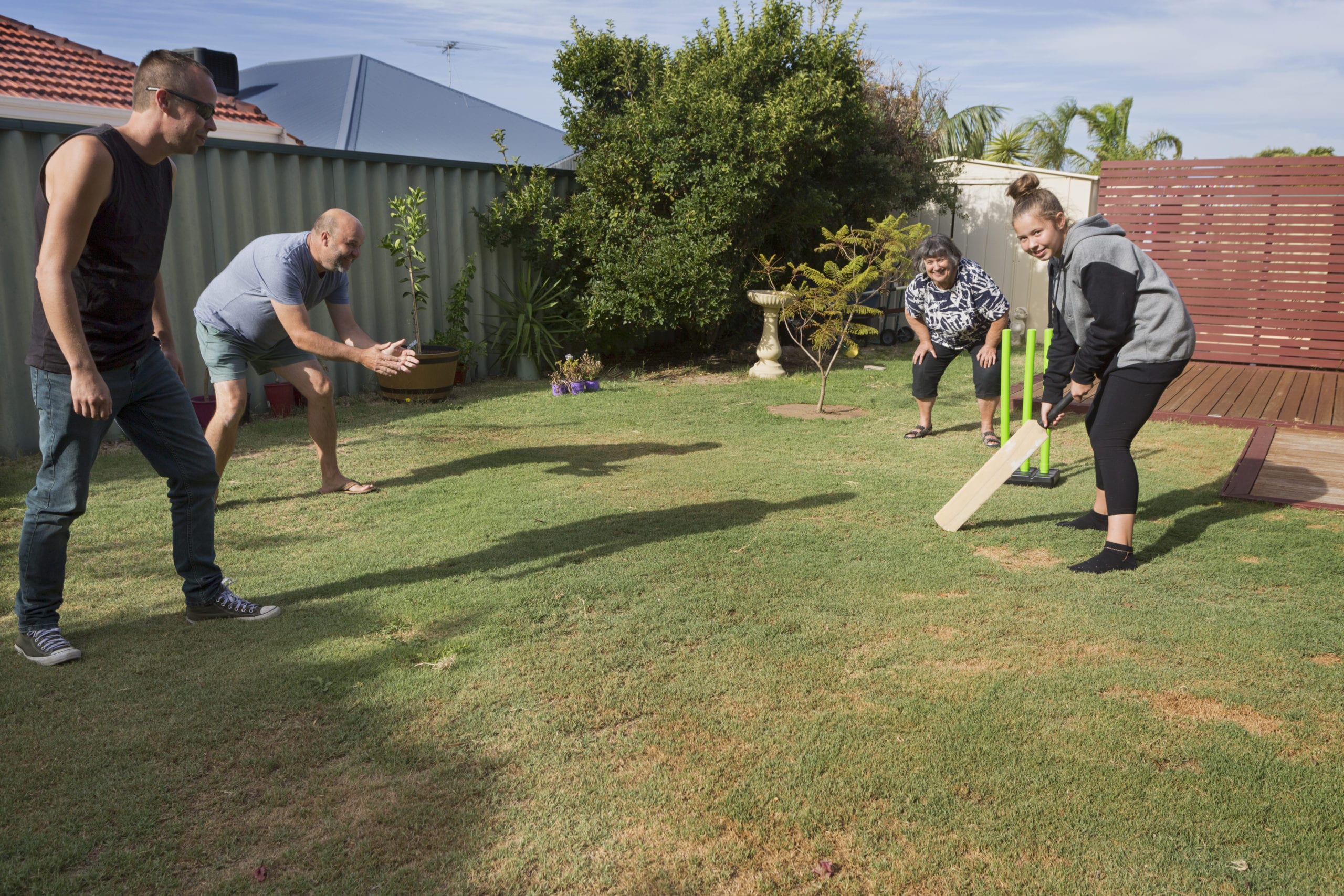 A family playing a traditional game of Back Yard Cricket.