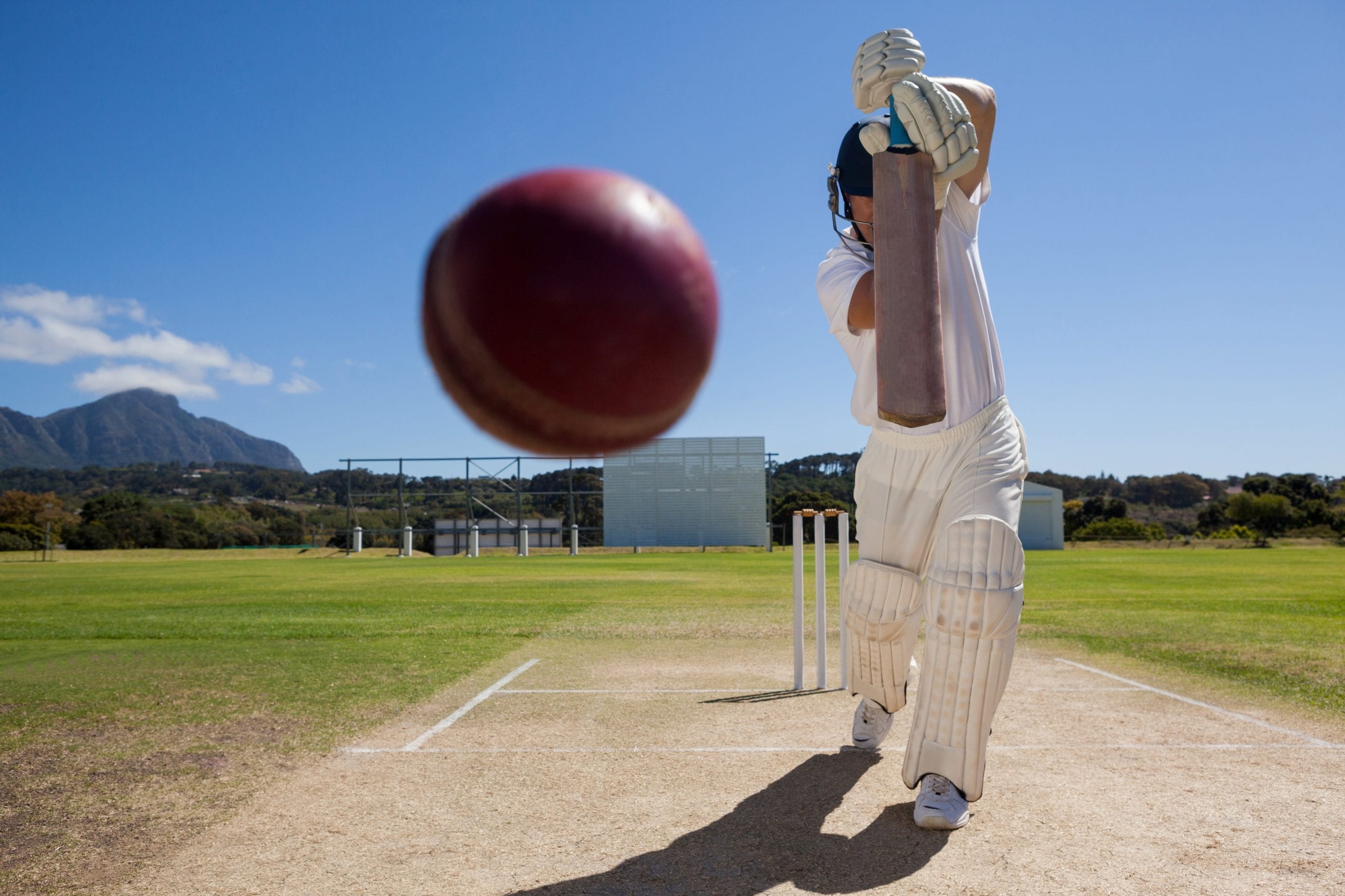 Full length of batsman playing cricket on pitch against blue sky